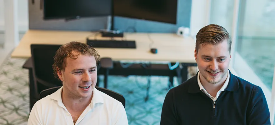 Twee collega's kijken samen naar een scherm